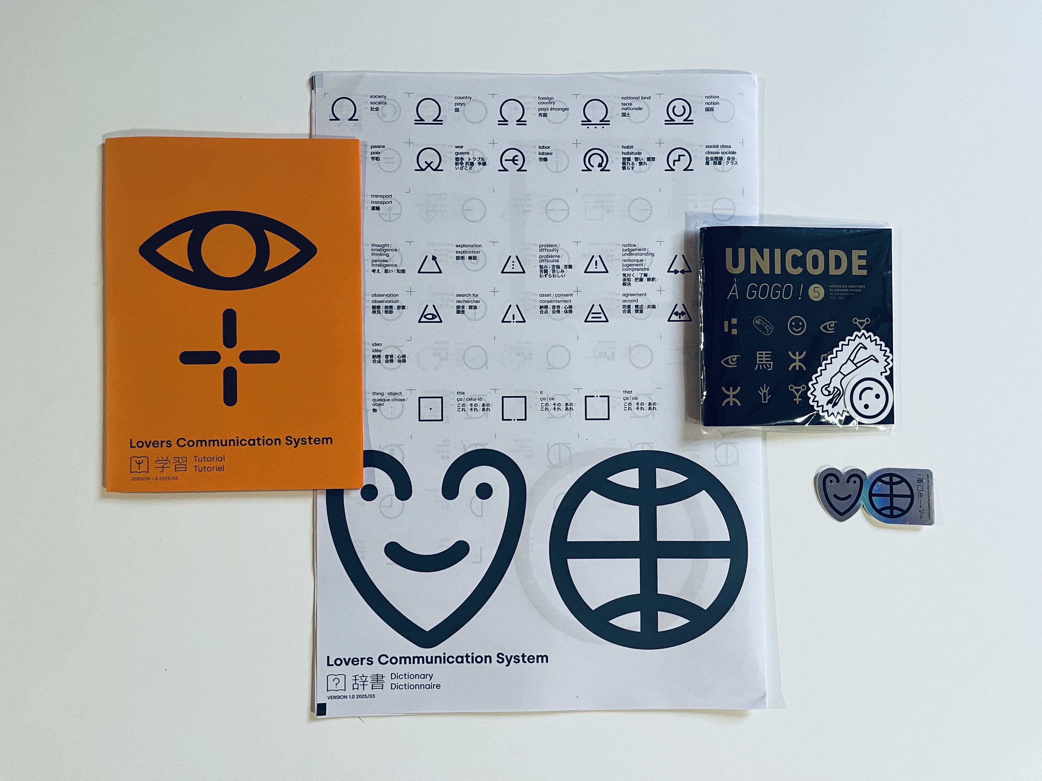 An arrangement of an orange A5 tutorial, an A3, black and white dictionary of LoCoS. Right next to it, the 5th edition of Unicode à Gogo! And a metallic LoCoS sticker that will be added to my bike asap!