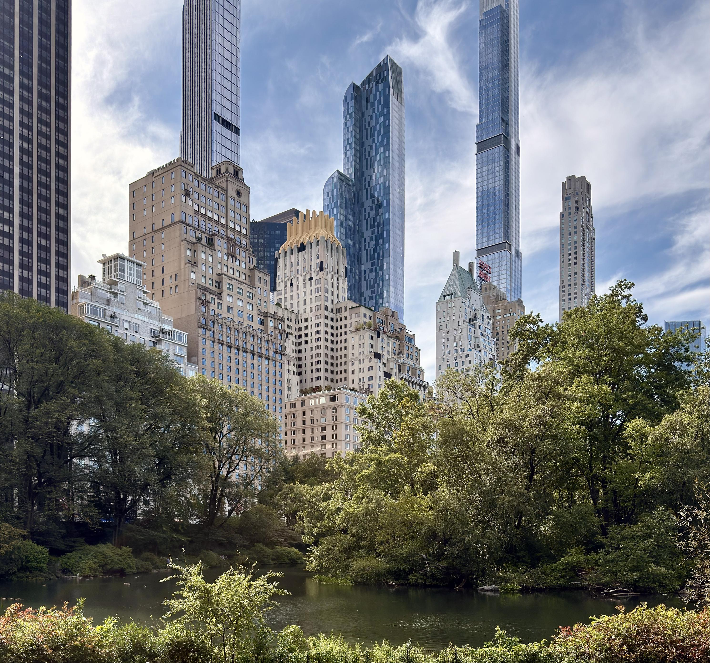 A color photograph in square aspect ratio. The scene is of The Pond in Central Park on a clear, sunny day. The pond's dark water reflects the surrounding late summer trees and the brilliant blue sky with scattered clouds. The foreground is dominated by lush, green trees and thick bushes. The eye is drawn to the path of the pond as it disappears behind the thick vegetation. In the midground, the historic, light-colored buildings of Central Park South rise above the park's treeline. Towering behind them are several prominent, modern skyscrapers with reflective glass facades. The tallest and most striking of these is Central Park Tower, a supertall residential building with a distinctive angular design, appearing to be one of the tallest structures on the New York City skyline. The iconic, gothic-inspired Hemet House building is visible, nestled among the taller towers. The scene beautifully contrasts the tranquility of Central Park's natural landscape with the imposing architecture of New York City's urban environment.