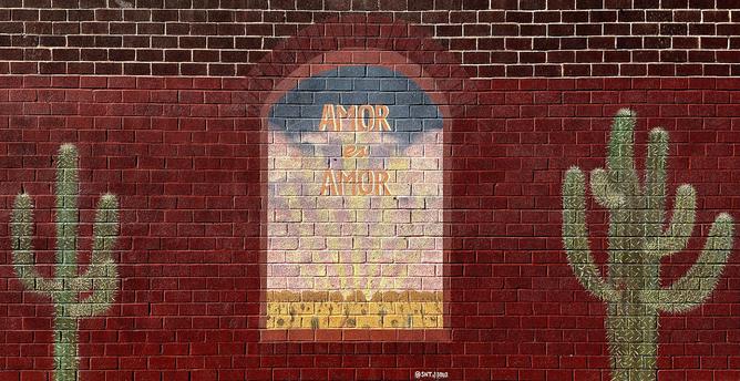 A color, wide-format landscape photograph of a mural painted on a brick wall taken on a sunny morning. The wall itself is a deep, uniform red-brick color with lighter white mortar lines, giving it a classic masonry look. The lower 3/4ths of the wall has been painted maroon red, and the left side is slightly faded, The central focus is a vertically oriented, arched window painted onto the wall, within it appears a soft, sunny scene. The arch frames a gradient of light blue at the top, fading into yellow and light pink in the middle, and ending with a band of dark yellow/orange at the bottom, and depicting a desert landscape filled with cactus and shrubs viewed through a window. Across this glowing area, the phrase "AMOR ES AMOR" (Spanish for "Love is Love") is painted in large, slightly stylized orange and gold block capital letters, stacked one above the other. On noth the left and right sides are two large, stylized paintings of cacti. The cacti are depicted using a light green paint that allows the red brick texture to show through, making them look almost like illuminated silhouettes. Both cacti have a central trunk and multiple curving arms. A small, white signature tag reads ‘@SNTJESUS’ is visible centered at the bottom edge of the arched window painting.