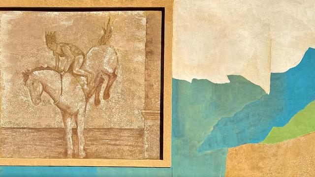 A color photograph in landscape orientation that captures a mural featuring a textured, multi-paneled design. On the left, a recessed rectangular frame contains a monochromatic, sepia-toned depiction of a figure riding a bucking horse. The rider is captured in mid-motion, leaning forward as the horse’s hind legs kick upward, rendered in a style reminiscent of a weathered stone relief. It depicts the controversial diving horse act on Steel Pier from the 1920s-1970s. The background within this frame has a mottled, sandy texture, and a decorative column is visible on the far right edge of the inset, adding a sense of depth. To the right of the framed scene, the mural transitions into a large-scale abstract composition. Large, jagged blocks of color overlap one another, including shades of cream, teal, seafoam green, and a bright, lime-colored accent. Below these shapes is a broad section of textured tan that resembles cracked earth. The overall color palette is earthy and coastal, reflecting a sun-bleached aesthetic. The entire work is applied to a heavily textured wall, which gives the colors and figures a rugged, weathered appearance.