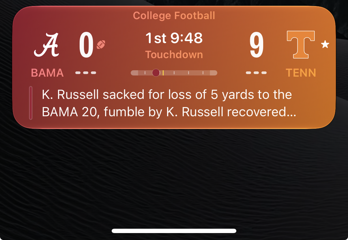 A cropped screenshot of a live activity displaying the Sports app on iOS 27 for the Alabama v Tennessee college football game. Bama 0 - Tenn 9.